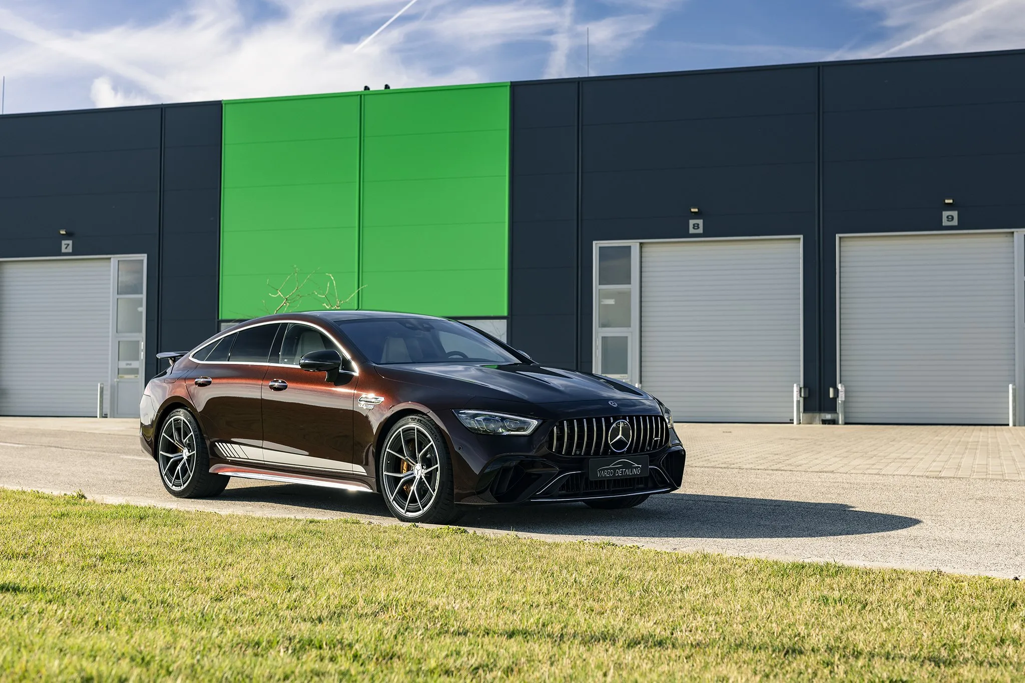Barna Mercedes-AMG GT négyajtós kupé oldalról a műhely előtt
