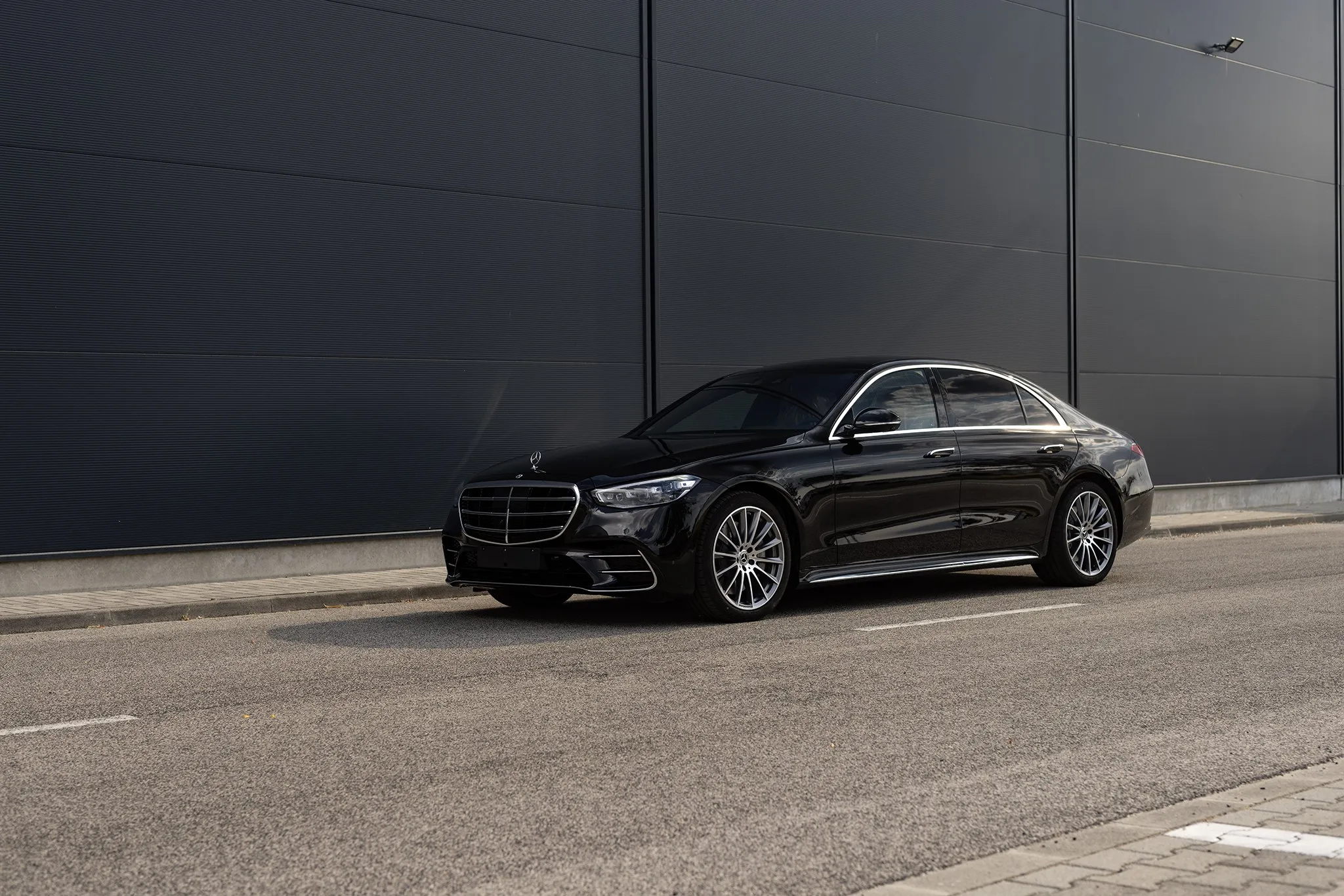 Fekete Mercedes S-osztály oldalról a műhely előtt