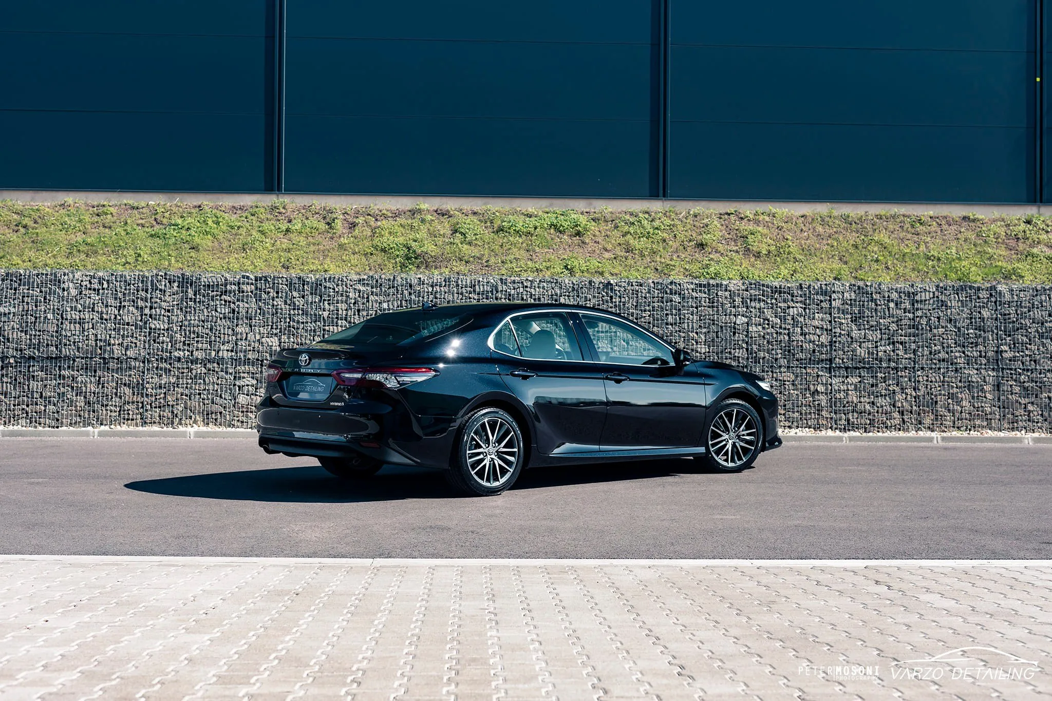 Fekete Toyota Camry kőfal előtt